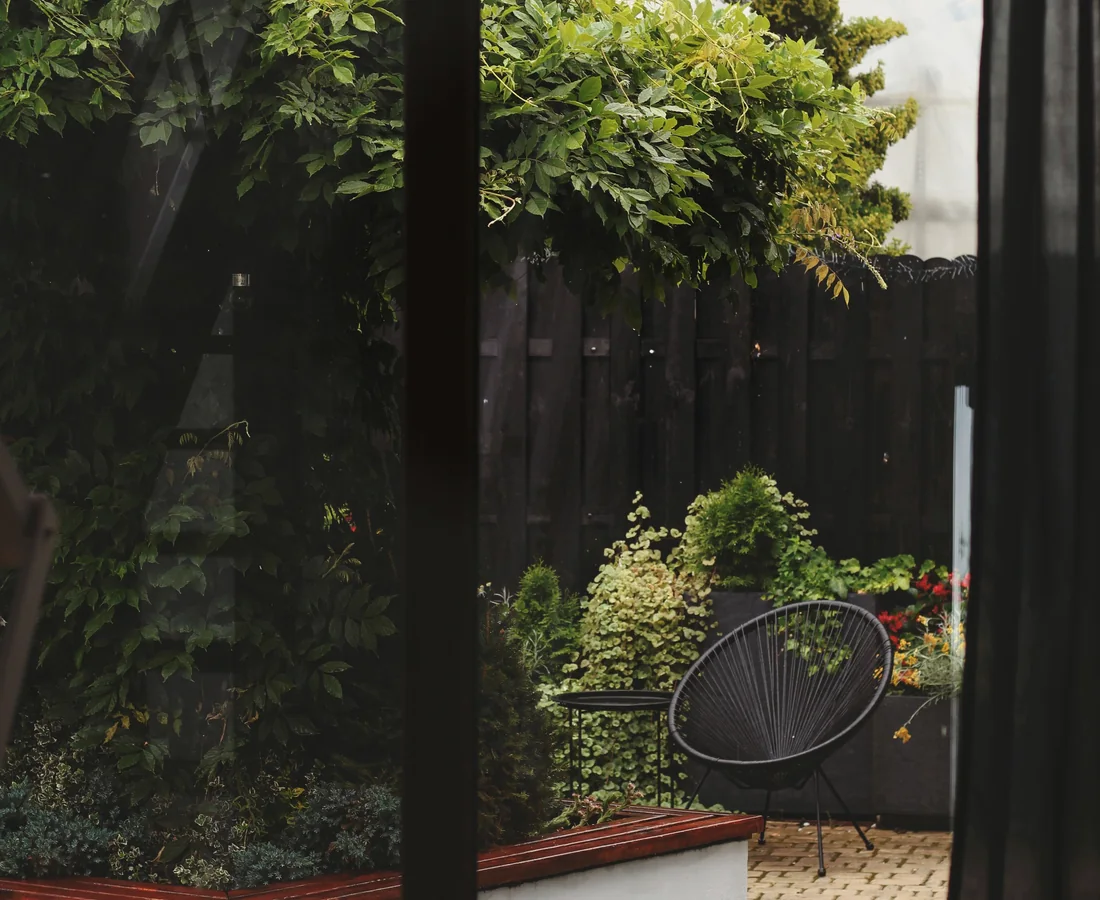 Blick durch eine Glastür in einen grünen privaten Garten
